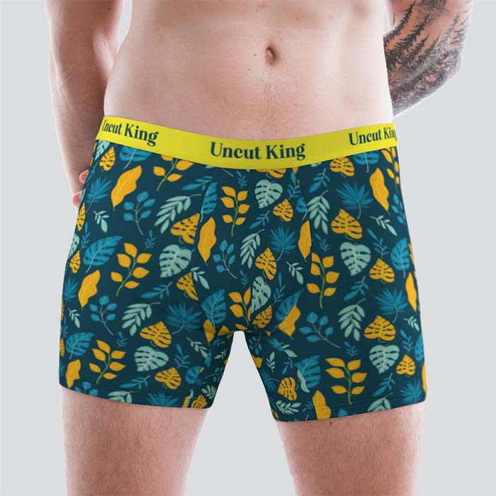 Man wearing a blue patterned pair of boxer briefs with a yellow waistband that says 'Uncut King'