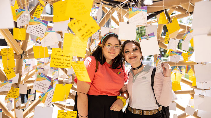Two women standing next to each other underneath hundreds of notecards.