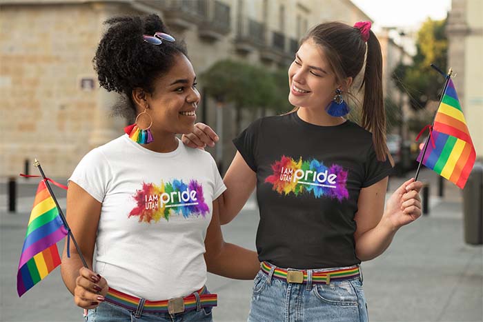 Two women wearing shirts with the pride logo