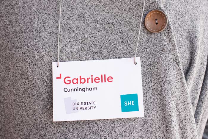 Woman wearing a nametag that says 'Gabrille Cunningham, Dixie State University' and has a 'she' pronoun sticker