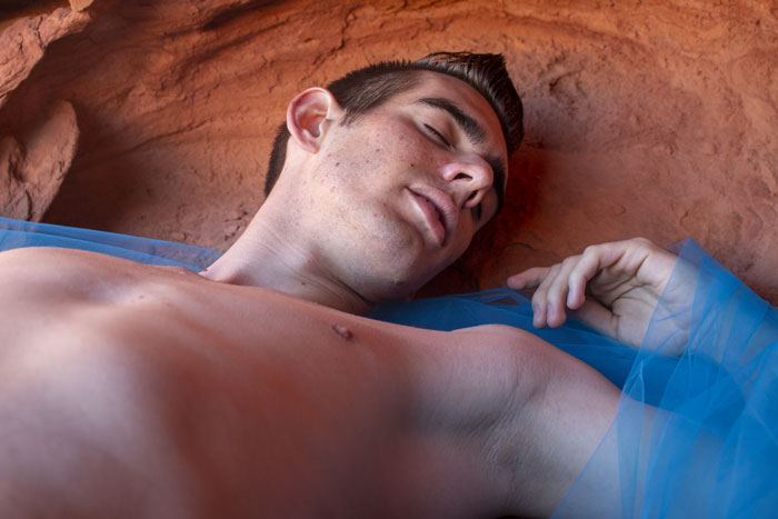 A man sleeping in a mountain crevice with a cyan cloth