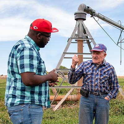 Image of two men standing in fron tof farm equipment