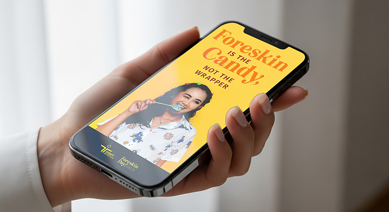 Personal holding a phone with an image of a woman eating a lollipop and the text 'Foreskin is the candy, not the wrapper'