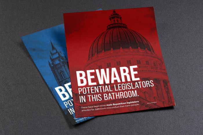 Red poster that says 'Beware potential legislators in this bathroom'. Behind it is a blue poster