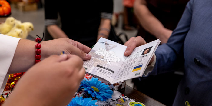 Person presenting a passport as another person adds a sticker to a page.